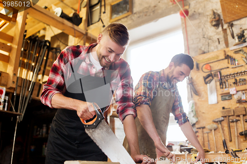 Image of carpenters working with saw and wood at workshop