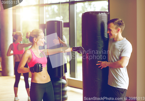 Image of smiling woman with personal trainer boxing in gym