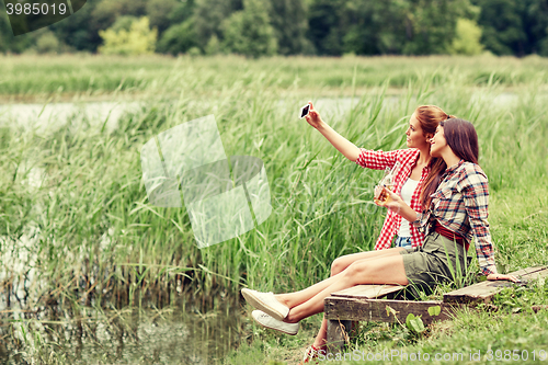 Image of happy women taking selfie by smartphone outdoors