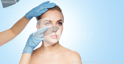 Image of surgeon or beautician hands touching woman face