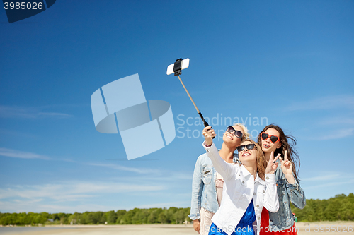 Image of group of smiling women taking selfie on beach