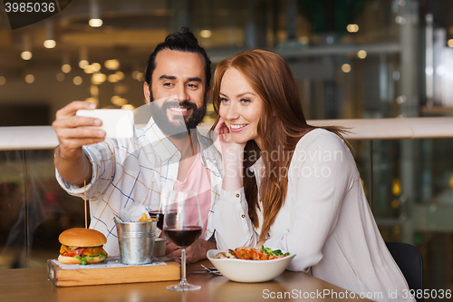 Image of couple taking selfie by smartphone at restaurant