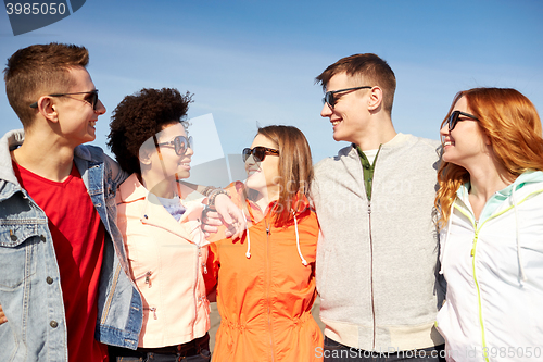 Image of happy teenage friends in shades talking on street