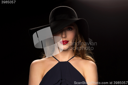 Image of beautiful woman in black hat over dark background