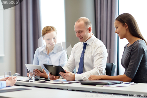 Image of smiling business people with tablet pc in office