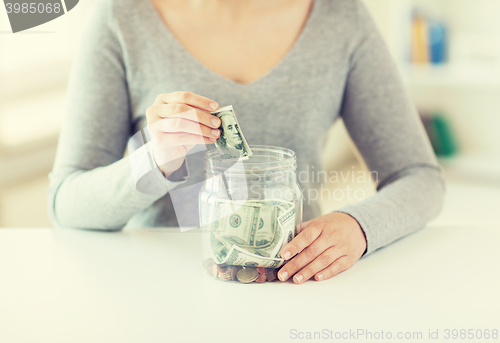 Image of close up of woman hands and dollar money in jar