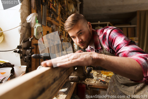 Image of carpenter working with wood plank at workshop