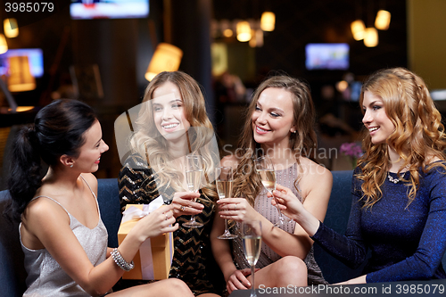 Image of happy women with champagne and gift at night club