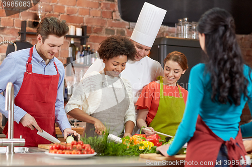 Image of happy friends and chef cook cooking in kitchen