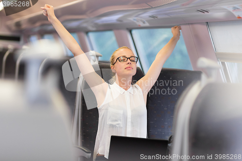 Image of Woman streching while travelling by train.