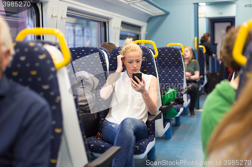 Image of Woman using mobile phone while travelling by train.