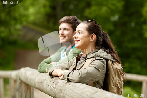 Image of smiling couple with backpacks on bridge in nature