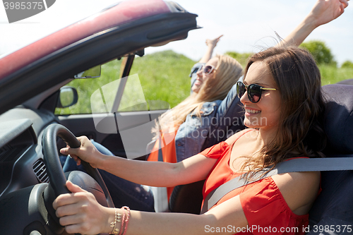 Image of smiling young women driving in cabriolet car