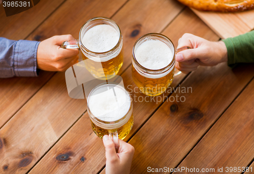 Image of close up of hands with beer mugs at bar or pub