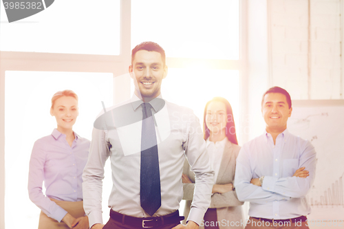 Image of smiling businessman in office with team on back