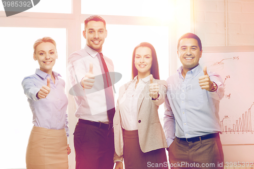 Image of business team showing thumbs up in office