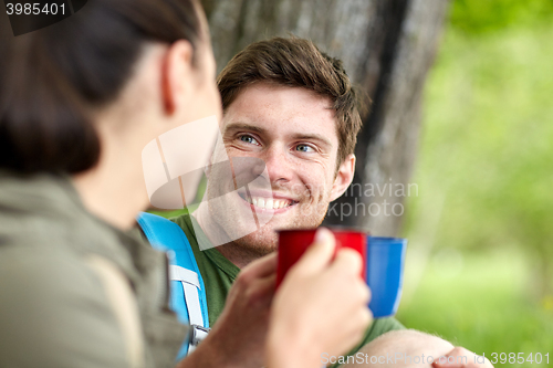 Image of happy couple with cups drinking tea in nature