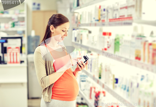 Image of happy pregnant woman with medication at pharmacy