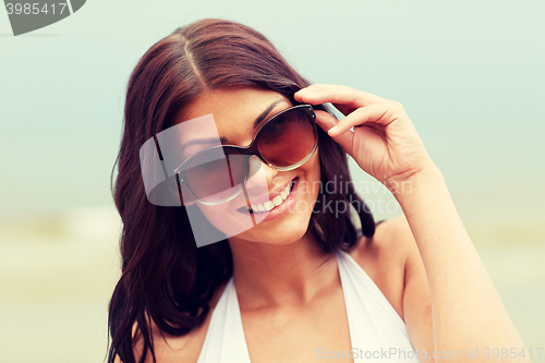 Image of smiling young woman with sunglasses on beach