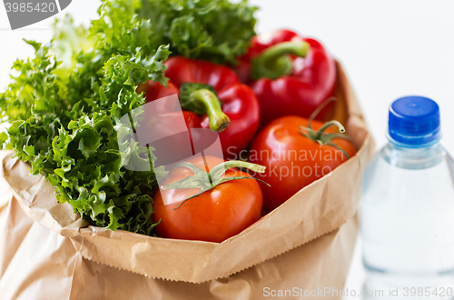 Image of close up of paper bag with vegetables and water