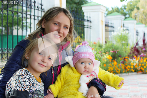 Image of happy mother sitting with her little daughters 