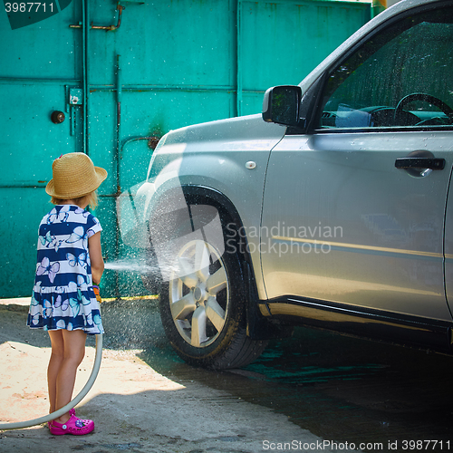 Image of Little girl helps her parents to wash the car