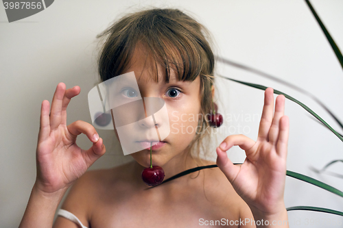 Image of Little girl with a cherry on her ears