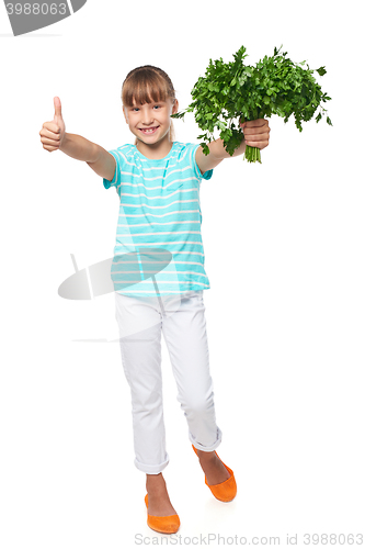 Image of Smilinglittle girl showing fresh parsley and gesturing thumb up