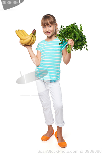 Image of Smiling little girl holding fresh parsley and bananas