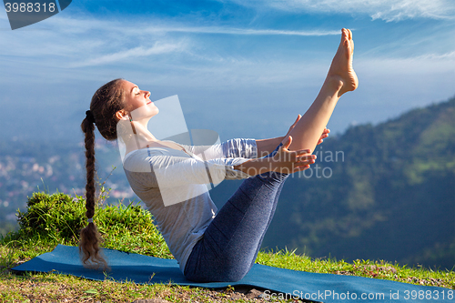 Image of Woman doing Ashtanga Vinyasa Yoga asana Navasana - boat pose