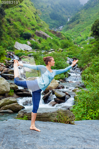 Image of Woman doing yoga asana Natarajasana outdoors at waterfall