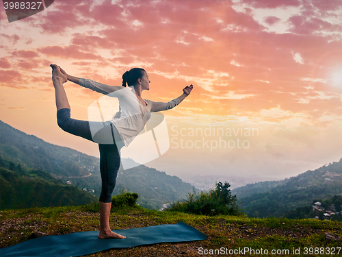 Image of Woman doing yoga asana Natarajasana outdoors at waterfall