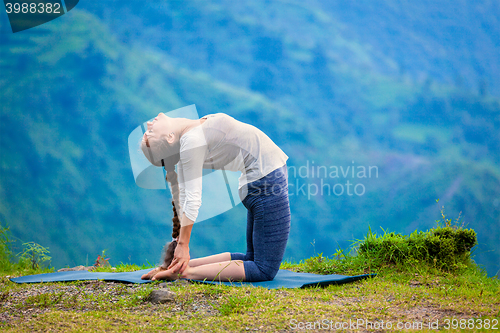 Image of Woman doing yoga asana Ustrasana camel pose outdoors