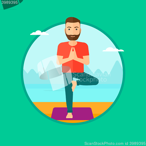 Image of Man practicing yoga tree pose on the beach.
