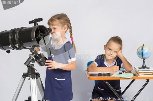 Image of Girl astronomer looks through the eyepiece of the telescope, the other girl thinking waiting for the results of observations