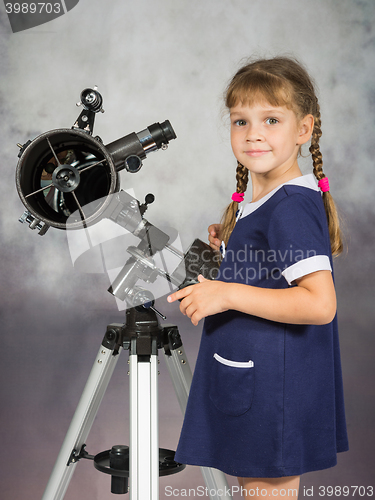 Image of Girl lover of astronomy stands next to the telescope and looked into the frame