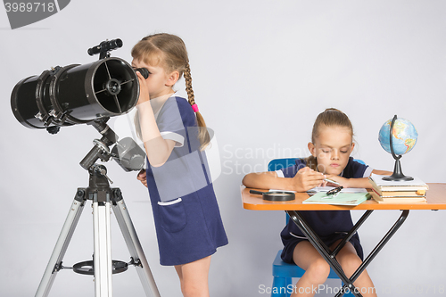 Image of Girl watching the celestial bodies in the telescope, the other girl is waiting for the results of observations