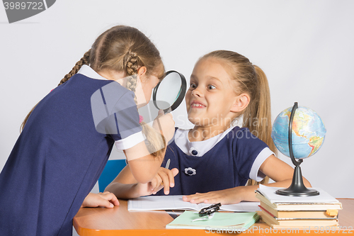 Image of Girl looking at the other girl with a magnifying glass on a geography lesson