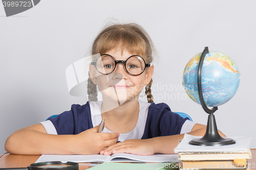 Image of Happy girl first grader sits at a table