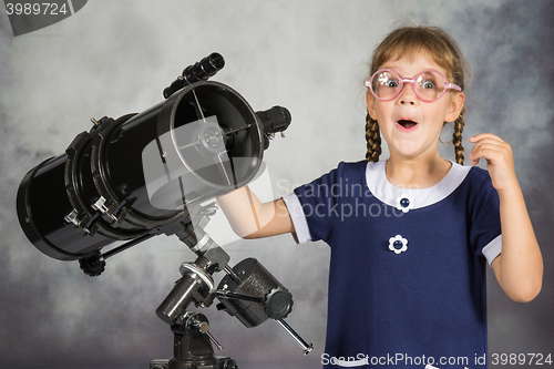 Image of Girl astronomer happily surprised by what he saw in the telescope