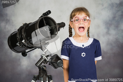 Image of Girl astronomer happily surprised by what he saw in the telescope