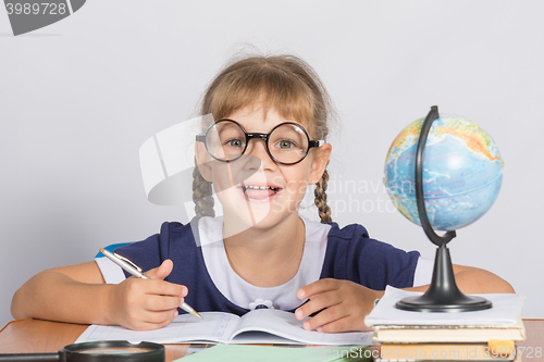 Image of Happy first grader sits at a table in the classroom, with his mouth open in pleasure