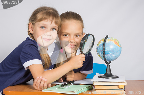 Image of Two schoolgirls looking at globe through a magnifying glass