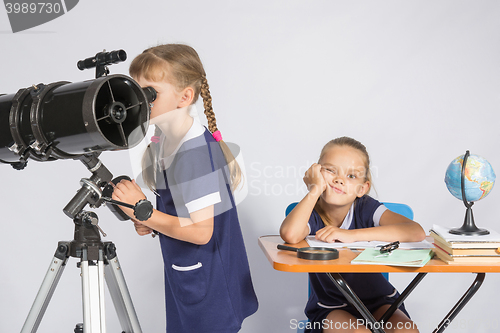 Image of A girl looks through a telescope, the other girl is waiting sad results