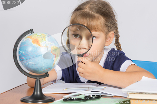 Image of Schoolgirl looking at globe through a magnifying glass