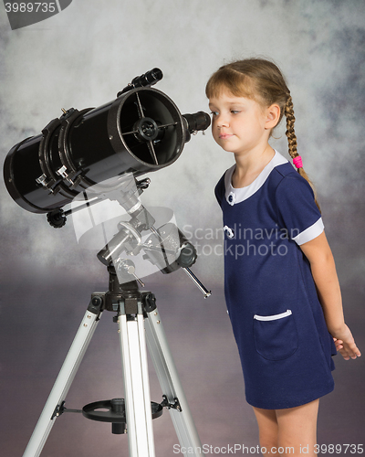 Image of Girl lover of astronomy with interest looks in the eyepiece of the telescope