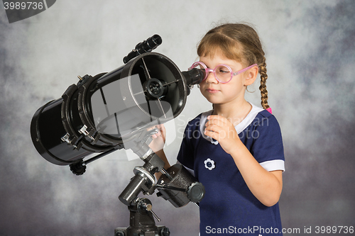 Image of Girl astronomer happily surprised by what he saw in the telescope