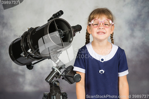 Image of Girl bespectacled amateur astronomer funny smiling standing by telescope