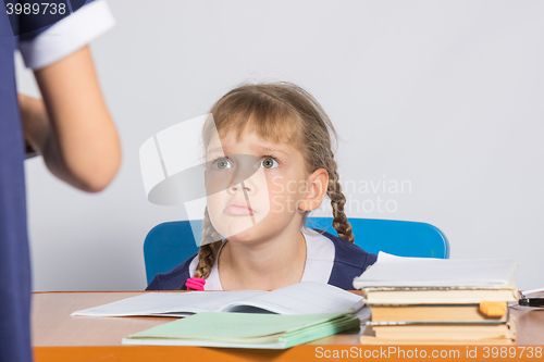Image of Schoolgirl sitting at the desk angrily looks at another girl