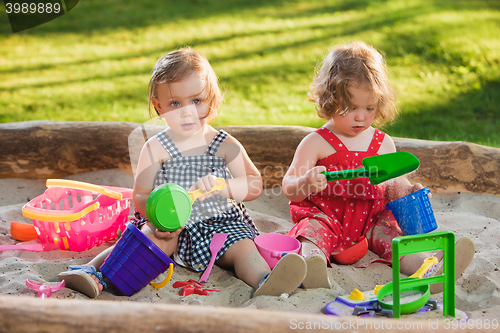 Image of The two little baby girls playing toys in sand